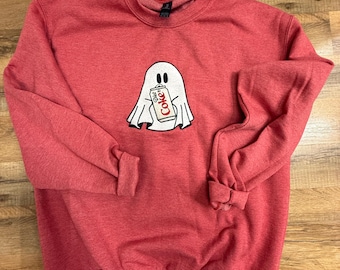 Op de afbeelding: Rode sweatshirt met een ronde hals en lange mouwen. Een witte spookafbeelding staat in het midden van de voorkant en houdt een Diet Coke-blikje vast. Het spook heeft zwarte ogen en een lachende mond. De sweatshirt is gemaakt van zacht materiaal.