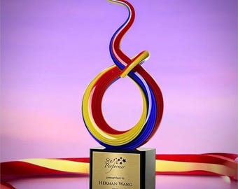 May include: A colorful award trophy with a black base and a swirling design in red, yellow, and blue. The trophy has a gold plaque that reads "Star Performer" and "presented to Herman Wang 2025". A red and yellow ribbon is draped around the base.