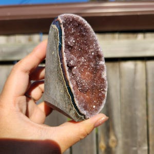 May include: A large amethyst geode with a purple and white crystal interior. The geode is cut in half and has a natural, rough exterior.