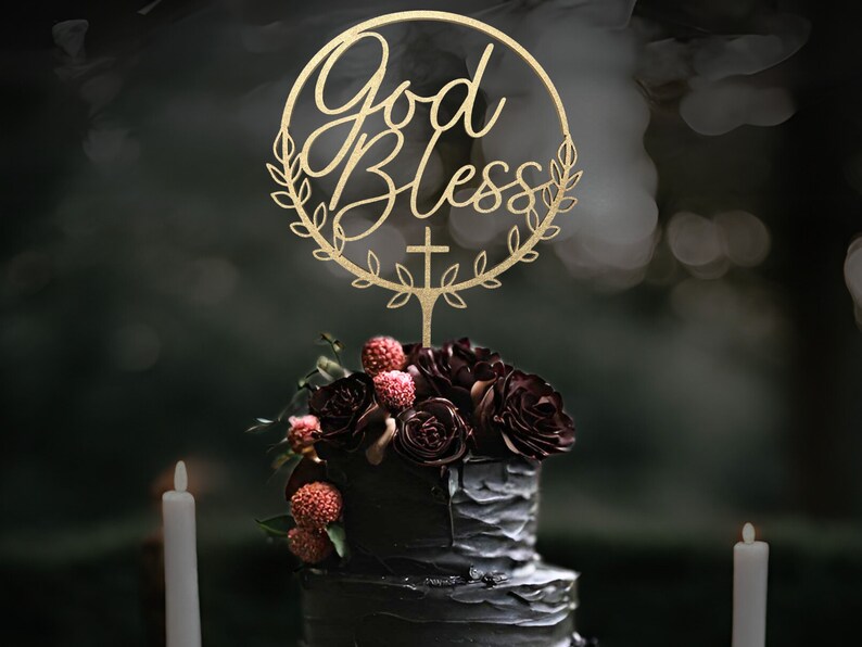 K&ouml;nnte beinhalten: Eine schwarze Hochzeitstorte mit roten und burgunderfarbenen Blumen, die mit einem goldenen Holz-Tortenaufsatz verziert ist, auf dem "God Bless" mit einem Kreuz und Bl&auml;ttern steht.