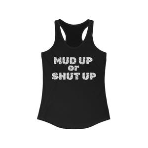 May include: Black racerback tank top with the text "MUD UP OR SHUT UP" in distressed white lettering. The tank top has a scoop neck and a racerback design, suitable for casual wear or workouts.