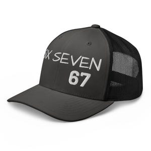 Può includere: Un cappellino trucker nero con pannello frontale rigido caratterizzato dal testo ricamato in bianco SIX SEVEN e dal numero 67 sottostante. Il cappello presenta una visiera curva e un pannello posteriore in rete nera traspirante regolabile.