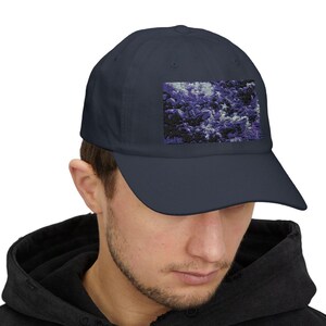 May include: A navy blue baseball cap with a purple and white abstract design on the front.