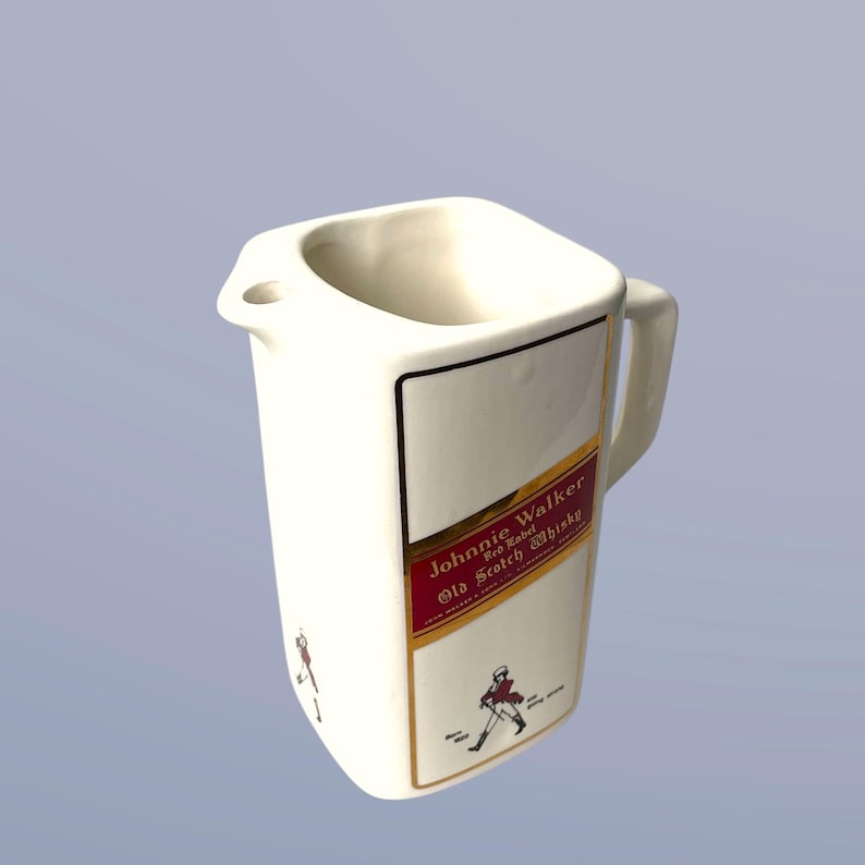Peut inclure: Pichet en c&eacute;ramique blanche avec une &eacute;tiquette Johnnie Walker Red Label Old Scotch Whisky. Le pichet a une forme carr&eacute;e et une poign&eacute;e.