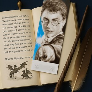 Puede incluir: Un marcapáginas temático de Harry Potter con un retrato de Harry Potter con una varita, colocado en un libro abierto. La escena incluye una varita, una pluma y un péndulo, todo sobre un fondo azul oscuro. El marcapáginas está numerado 2/100.