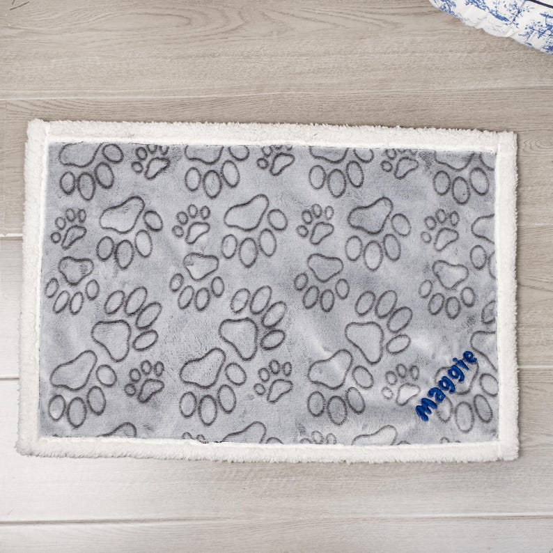 May include: Gray and white pet blanket with a paw print pattern and the name "Maggie" embroidered in blue.
