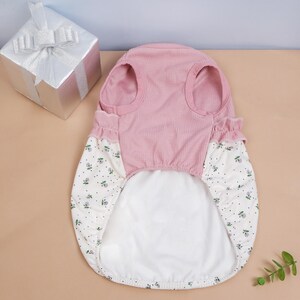 Peut inclure: Un haut pour animal de compagnie avec un corsage en maille gaufr&eacute;e rose poudr&eacute;, dot&eacute; d'une encolure ronde et d'emmanchures. La partie inf&eacute;rieure est en tissu blanc &agrave; petites fleurs roses et vertes avec des points noirs, orn&eacute;e d'un volant.