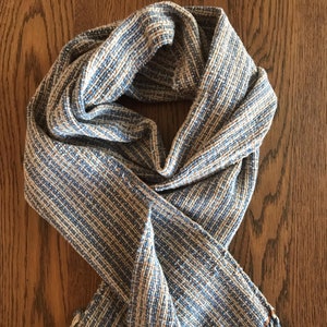 May include: A blue and white striped scarf with a brown stripe and fringe on the ends.