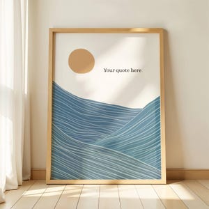 May include: A framed art print featuring an abstract landscape. The artwork depicts a tan sun and blue wavy lines, resembling ocean waves, against a cream background. The text "Your quote here" is printed on the artwork. The frame is made of light-colored wood.