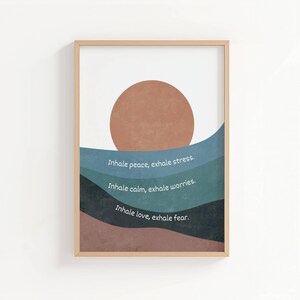 Peut inclure: Impression d'art encadrée avec un design minimaliste. Elle présente un grand soleil brun circulaire au-dessus de formes bleues et marron superposées. L'œuvre comprend le texte : "Inhale peace, exhale stress," "Inhale calm, exhale worries," et "Inhale love, exhale fear."