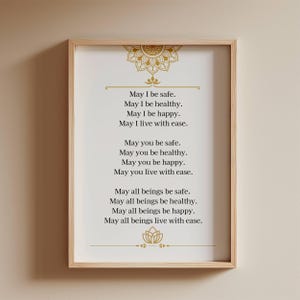 May include: A framed print with a light wood frame. The print has a cream background with gold decorative elements at the top and bottom. The text reads "May I be safe...May all beings live with ease."