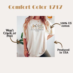 May include: An off-white t-shirt featuring a graphic of four geese carrying various items. Below the geese, the text reads, I DO A LITTLE BIT OF EVERYTHING Ms. Emily. The shirt is labelled as Comfort Color 1717, 100% US cotton, produced in USA, and won't crack or peel.