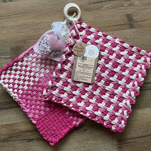 May include: Two pink and white woven pot holders with a small pink heart-shaped tag that says "Hand Made".