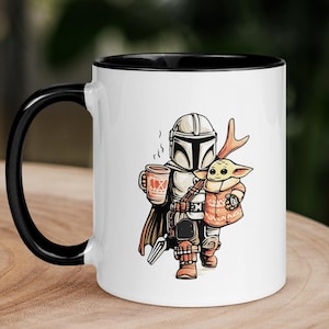Op de afbeelding: Witte keramische mok met een zwart handvat en rand. De mok heeft een cartoon illustratie van een Mandalorian personage met een koffiekopje en Grogu. De beker heeft de tekst "4X" erop. De mok staat op een houten oppervlak.