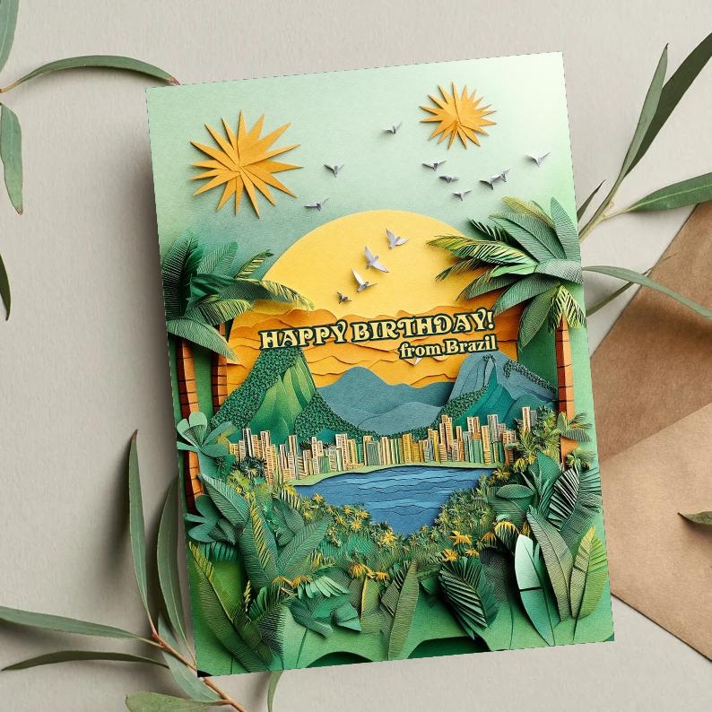 May include: A layered paper art birthday card with a Brazilian theme. The card features a yellow sun, palm trees, and the text "HAPPY BIRTHDAY! from Brazil." The design includes a cityscape, mountains, and a lake, all in shades of green, blue, and yellow.
