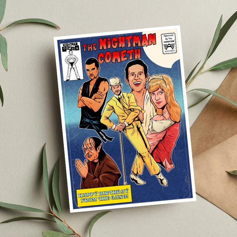 以下が含まれることがあります： 青い背景に「The Nightman Cometh」というタイトルが書かれたコミックの表紙。表紙には、黒い空手着を着た男性、黄色のスーツを着た男性、赤いドレスを着た女性、緑色の肌をした尖った耳の男性の4人のキャラクターが描かれている。「Happy Birthday from the Gang!」というテキストが表紙の下部に書かれている。