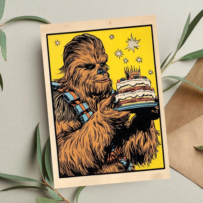 May include: A vintage-style birthday card featuring Chewbacca holding a layered cake with candles. The illustration has a yellow background with star accents. The card has a beige border and is set against a neutral background.