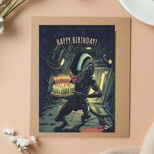 Puede incluir: Tarjeta de cumplea&ntilde;os con una ilustraci&oacute;n de un alien&iacute;gena sosteniendo un pastel de cumplea&ntilde;os con velas encendidas. La tarjeta tiene el texto "HAPPY BIRTHAY!" en blanco. El fondo muestra un interior futurista.