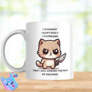 May include: White ceramic coffee mug with a cartoon illustration of a brown cat holding a knife. The text on the mug reads "I'm hungry, I slept badly, I'm stressed. Today I will choose the path of violence."