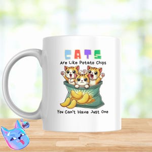 Puede incluir: Taza de cerámica blanca con un gráfico colorido de tres gatos de dibujos animados dentro de una bolsa de patatas fritas. El texto "CATS Are Like Potato Chips You Can't Have Just One" está impreso en la taza.
