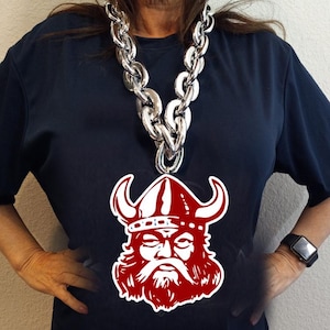 May include: A silver chain necklace with a large, red Viking head pendant. The pendant has a white helmet and beard.