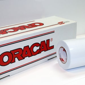 May include: A white roll of vinyl and a white box with the word "ORACAL" in red letters. The box has red and black stripes. The roll of vinyl is on a white background.