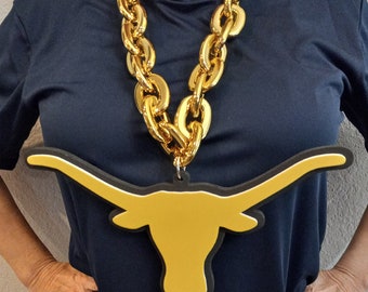 May include: A gold chain necklace with a large gold Longhorn head pendant. The pendant is made of foam and has a black outline.