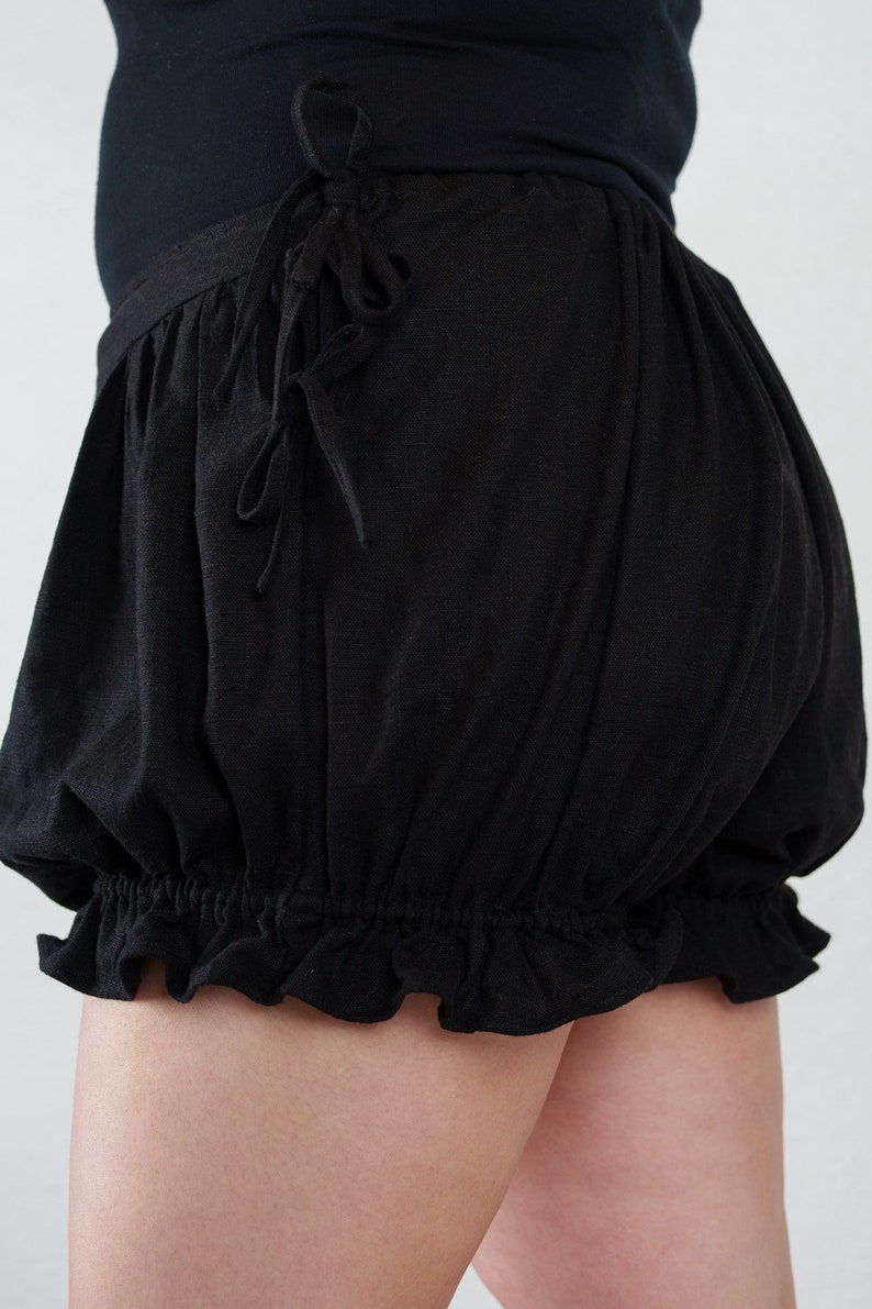 May include: Black cotton shorts with a ruffled hem and a drawstring tie at the waist.