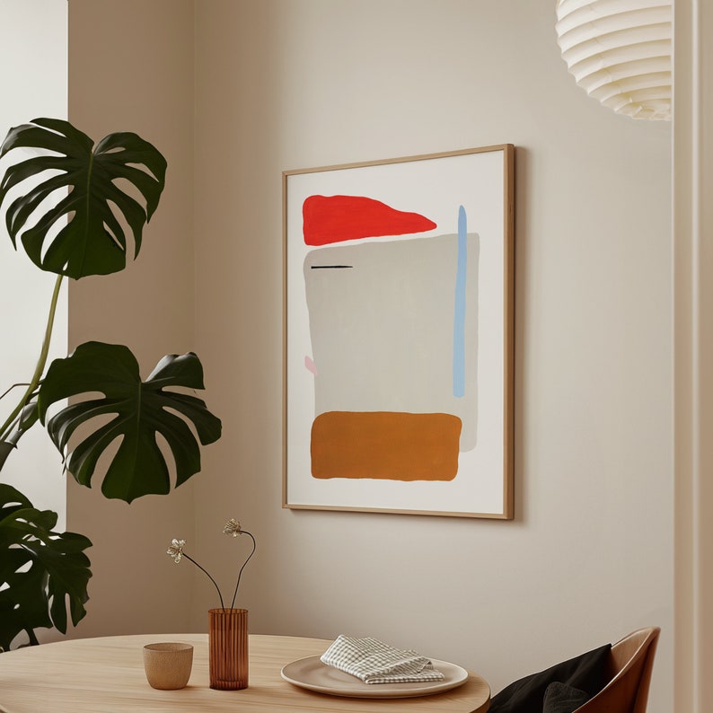 May include: A framed abstract painting with a light gray background, a red, orange, and blue geometric design, and a brown rectangle at the bottom.