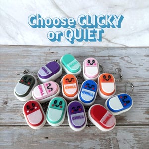 May include: A collection of colorful pill-shaped keychains with smiling faces and the word "CHILL" on them. The keychains are in various colors, including green, purple, pink, orange, blue, and red. The text "Choose CLICKY or QUIET" is at the top.