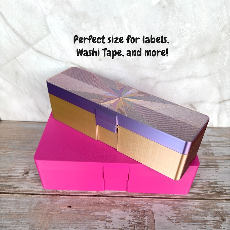 May include: A two-piece storage box set. The top box is rectangular with a gold base, purple accents, and a patterned lid. The bottom box is a bright pink, rectangular container. Text on the image reads: Perfect size for labels, Washi Tape, and more!