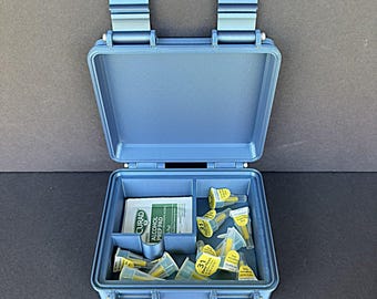 May include: Open blue plastic case with a divided interior. The case contains alcohol prep pads and several yellow and white syringes. The case has two blue clasps on the top and is open, revealing the contents.