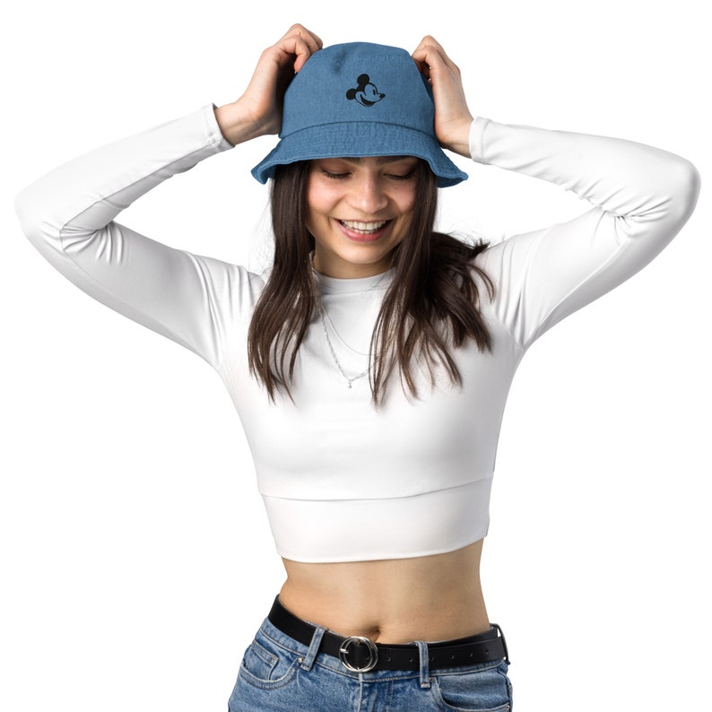 Woman wearing Blue Denim bucket hat with embroidered retro Mickey Mouse profile and a white crop top