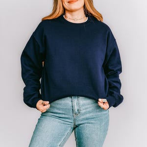 K&ouml;nnte beinhalten: Ein marineblaues Sweatshirt mit Rundhalsausschnitt und langen &Auml;rmeln. Das Sweatshirt wird mit hellblauen Jeans kombiniert. Das Outfit ist schlicht und l&auml;ssig, geeignet f&uuml;r den Alltag.