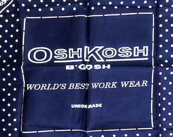 May include: A dark blue bandana featuring a white polka dot border and a central rectangular frame. The text reads OSHKOSH B'GOSH, WORLD'S BEST WORK WEAR, and UNION MADE in white lettering. The design includes a dashed line border around the text.