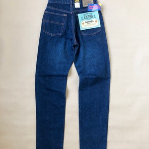 Peut inclure: Jean en denim bleu foncé avec une coupe droite. Le jean a une conception classique à cinq poches, une braguette boutonnée et une étiquette de taille 30. Le dos comporte deux poches et un patch en cuir.
