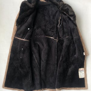 Puede incluir: Una chaqueta de ante marr&oacute;n con forro de piel sint&eacute;tica. La chaqueta est&aacute; abierta y el forro es visible. La chaqueta tiene una etiqueta que dice "Aero Leather Co."