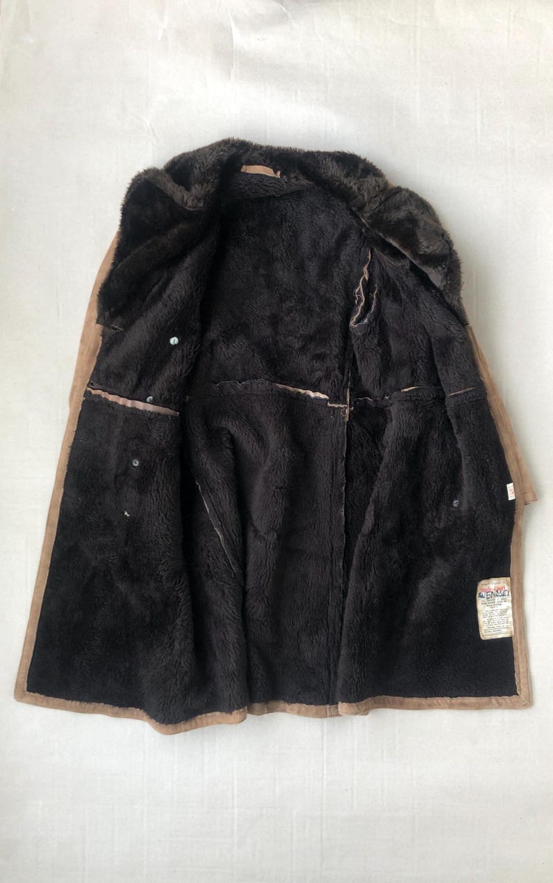 Puede incluir: Una chaqueta de ante marr&oacute;n con forro de piel sint&eacute;tica. La chaqueta est&aacute; abierta y el forro es visible. La chaqueta tiene una etiqueta que dice "Aero Leather Co."