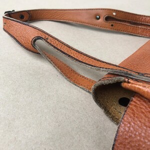 May include: A brown leather shoulder bag with a flap closure and a single strap. The bag has a textured surface and dark brown stitching detail.
