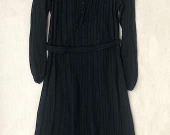 May include: A black ribbed knit dress with a white collar and long sleeves. The dress has a button fastening at the front and a belt at the waist.