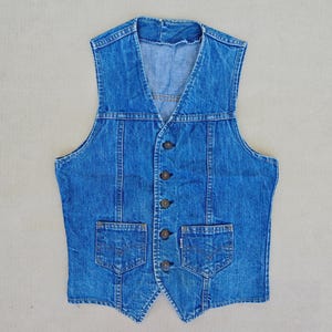 Vintage Levi's jeansväst storlek S. Blå bomullsjeansväst, knappar framtill, justerbar rem baktill