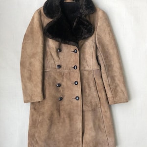 Puede incluir: Un abrigo de gamuza marr&oacute;n con cuello de piel sint&eacute;tica marr&oacute;n y botones de doble botonadura.