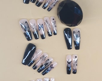 May include: A collection of artificial nails with a butterfly design. The nails feature a gradient from a light pink to a dark navy blue. The butterfly design is in black and blue, with floral accents.