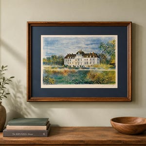 Peut inclure: Une impression aquarelle encadrée représentant un château blanc au toit sombre situé derrière un plan d'eau. L'œuvre est entourée d'un passe-partout bleu foncé et d'un cadre en bois brun, révélant des coups de pinceau détaillés de feuillage.