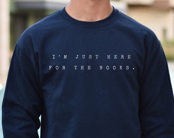 May include: Navy blue long-sleeved sweatshirt with the text "I'm just here for the books." printed in white.