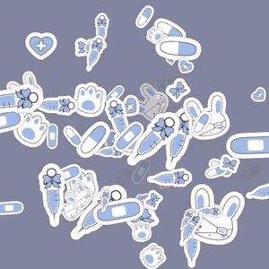 Pode incluir: Uma coleção de adesivos brancos com detalhes em azul claro, apresentando designs médicos e com tema de coelhos. Inclui seringas, pílulas, bandagens, rostos de coelhos com máscaras, pegadas de patas e formas de coração. Os adesivos estão espalhados em um fundo cinza.