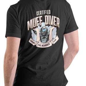 May include: Black t-shirt with a white graphic of a scuba diver with the text "Certified Muff Diver" and "Explore the Bearded Clam Deep".