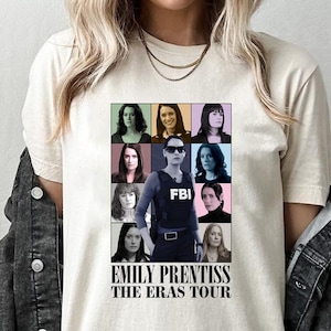 May include: A white t-shirt with a collage of images of a woman in different outfits and hairstyles. The text "Emily Prentiss The Eras Tour" is printed below the collage.
