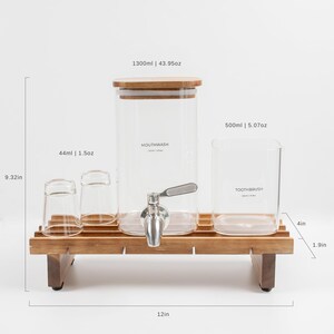 May include: A wooden stand with two glass jars, one labeled "Mouthwash" and the other "Toothbrush". The stand has a dispenser tap and two smaller glass cups. The stand is 12 inches long, 4 inches wide, and 1.9 inches tall.