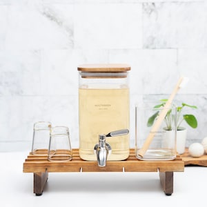 May include: A wooden countertop with a glass dispenser labeled "MOUTHWASH" and a glass jar labeled "TOOTHBRUSH". There are two small glass cups and a wooden toothbrush on the countertop. The countertop is on a wooden stand.